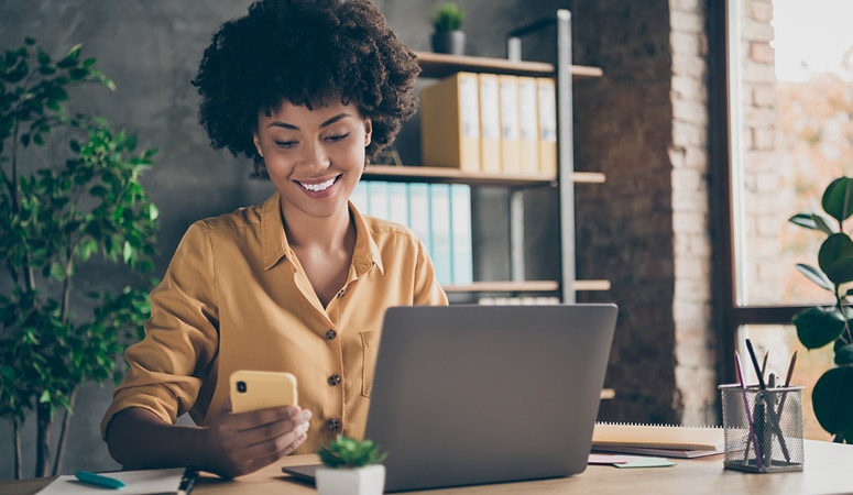 Photo of cheerful professional business lady in yellow shirt working as smm manager in a large international company browsing through telephone in search of appropriate content